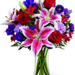 Bouquet of red roses and pink lilies in a clear glass vase