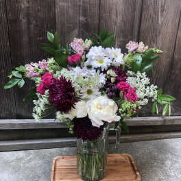 Mixed bouquet in a clear glass vase with white, pink, and burgundy flowers
