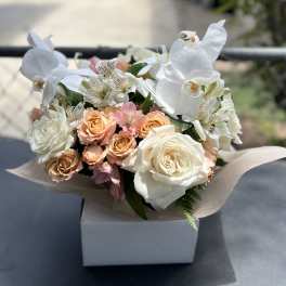 White orchids and peach roses arranged in a box