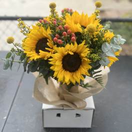 Bouquet of sunflowers with pink berries and eucalyptus in kraft paper