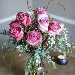 Pink roses arranged in a glass vase with airy filler flowers