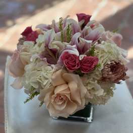Pink and white bouquet with roses, lilies, and hydrangeas in a square vase