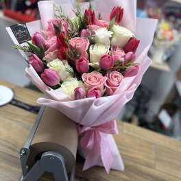 Pink and white rose bouquet with red tulips wrapped in pale pink paper
