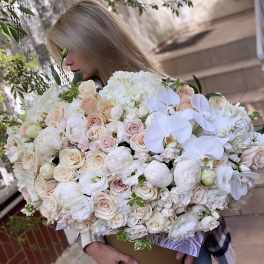 Woman holding a large bouquet of white and blush flowers in a box