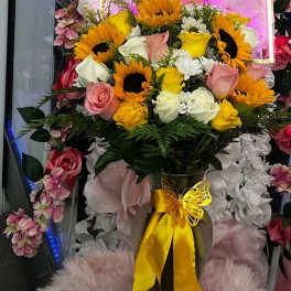 Bouquet of sunflowers and roses with a yellow ribbon in a vase