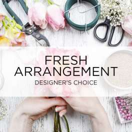 Hands holding pink tulips beside floral arranging tools and supplies