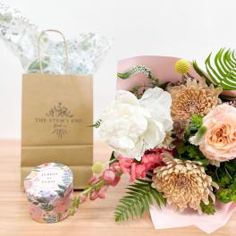 Bouquet of peach and white flowers with a candle and gift bag