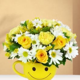 Yellow and white flower arrangement in a smiley-face mug