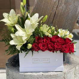 Red roses and white lilies arranged in a white box