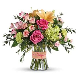 Pink roses and lilies arranged in a clear glass vase