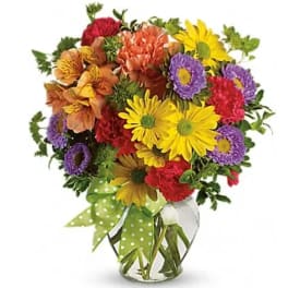 Colorful mixed bouquet in a clear glass vase with a green polka-dot ribbon