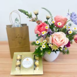 Mixed bouquet in a white vase with a box of Ferrero Rocher chocolates