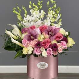 Pink and white mixed flower arrangement in a round pink box