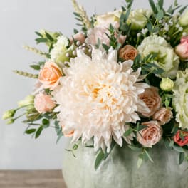 Bouquet of pale peach and white flowers in a round vase