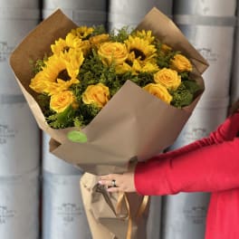 Bouquet of yellow sunflowers and roses wrapped in brown paper