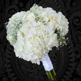 White bridal bouquet with hydrangeas and roses wrapped in white ribbon