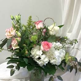 Pink and white roses with white hydrangeas in a glass vase