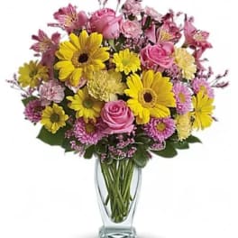 Bouquet of pink roses and yellow daisies in a clear glass vase