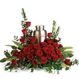 Red roses arranged around a silver urn with greenery