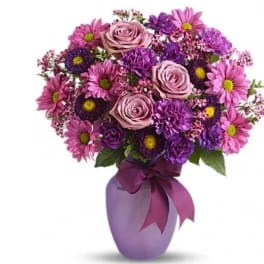 Pink and purple bouquet in a lavender vase with a ribbon