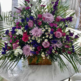 Large mixed bouquet in a woven basket with pink, purple, and white flowers
