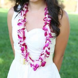 Woman wearing a pink and white orchid lei over a white dress