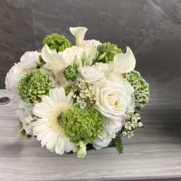 White and green floral arrangement with roses, calla lilies, and a gerbera daisy