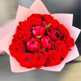 Bouquet of red roses and red peonies wrapped in pale pink paper
