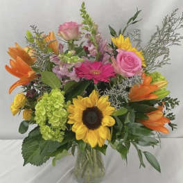 Mixed bouquet with sunflowers, pink roses, orange lilies, and a glass vase