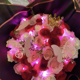 Bouquet of red and pink roses with butterfly decorations and a gold crown