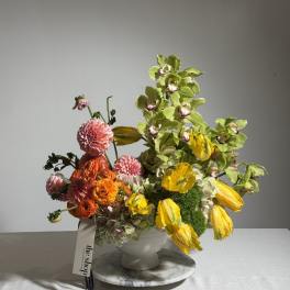 Colorful floral arrangement in a white vase with yellow and pink blooms