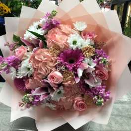 Large bouquet of pink and white flowers wrapped in pale pink paper