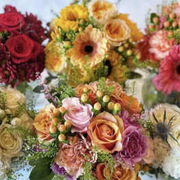 Assorted bouquets of roses, gerbera daisies, and carnations in warm colors