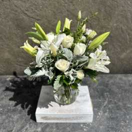 White roses and lilies arranged in a clear glass vase