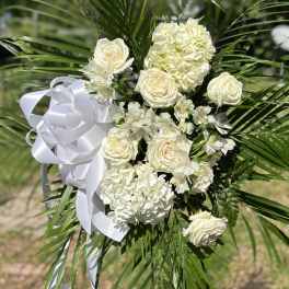White floral standing spray with roses, hydrangeas, and ribbon