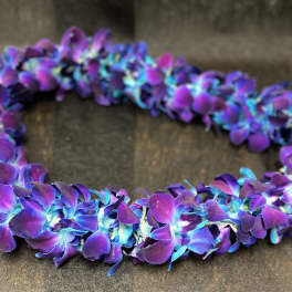 Purple and blue flower lei on a dark surface