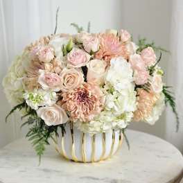 Blush and white floral arrangement in a gold-trimmed vase
