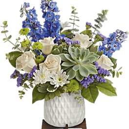 Blue and white floral arrangement in a white vase with a succulent