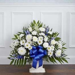 White floral standing spray with a blue ribbon on a pedestal base