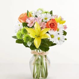 Bouquet of mixed flowers in a clear glass vase with a ribbon