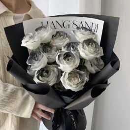 Bouquet of white roses wrapped in black paper