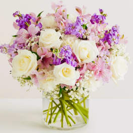 Pink and purple bouquet with white roses in a clear glass vase