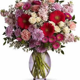Mixed pink, purple, and red flowers in a glass vase