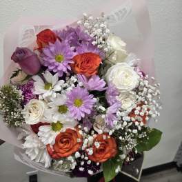 Mixed bouquet of roses and daisies wrapped in pale pink paper