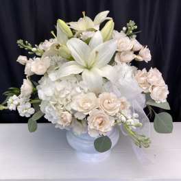 White lilies and pale blush roses in a white vase