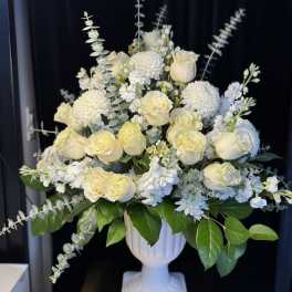 White roses and pompom mums in a white pedestal vase