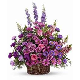 Purple and pink mixed flower arrangement in a wicker basket