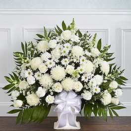 Large white floral arrangement in a white vase with a satin ribbon