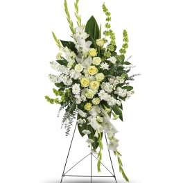 Tall white and pale yellow funeral spray on a stand