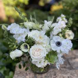 White floral bouquet in a glass vase with green accents